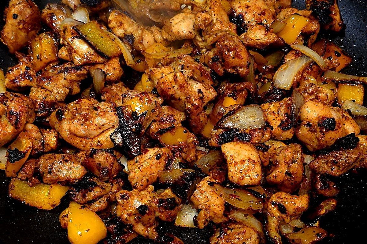 Charred fajita-seasoned chicken thighs with onion and bell pepper in a skillet