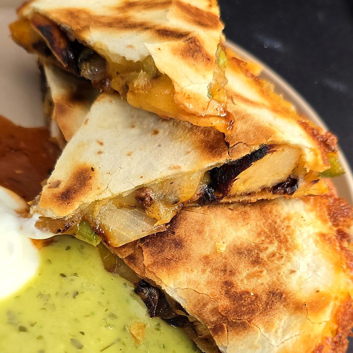 Stacked chicken fajita quesadilla wedges showing charred chicken, peppers and melted Colby Jack