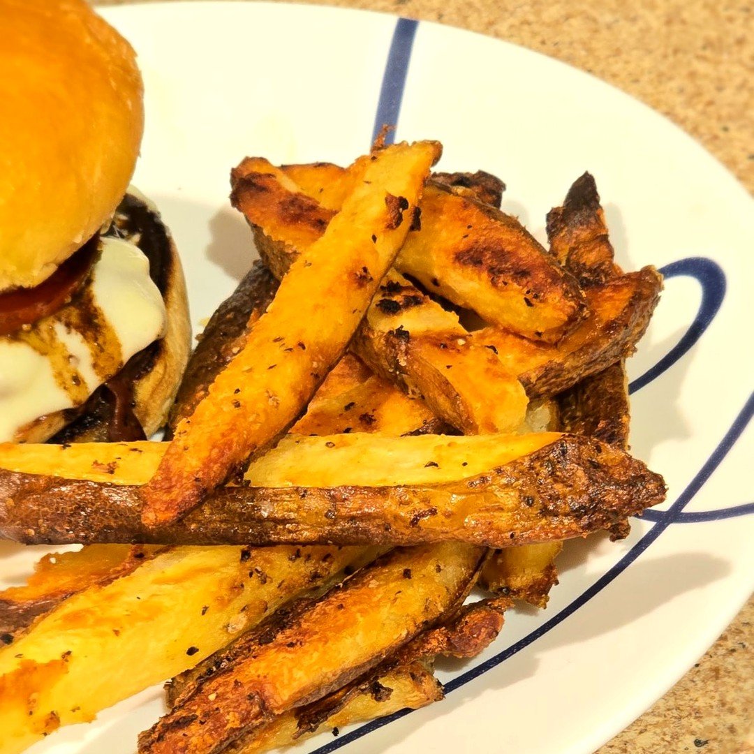 Extra crispy oven baked fries, golden and skin-on, on a white plate