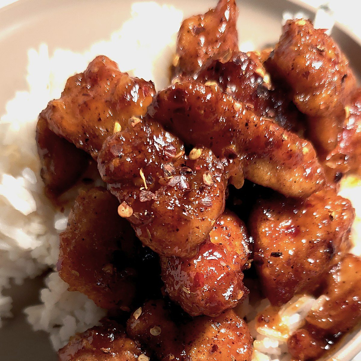 Crispy firecracker chicken over white rice in a bowl