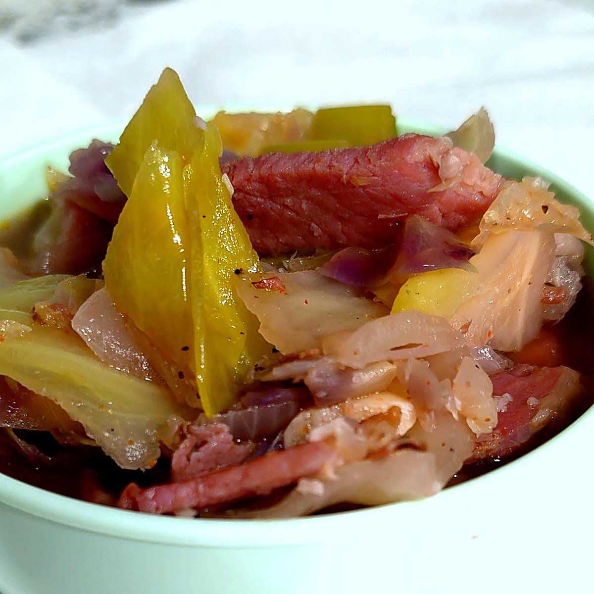 Close-up of ham and cabbage soup with seared ham, tender green cabbage and red onion in savory broth