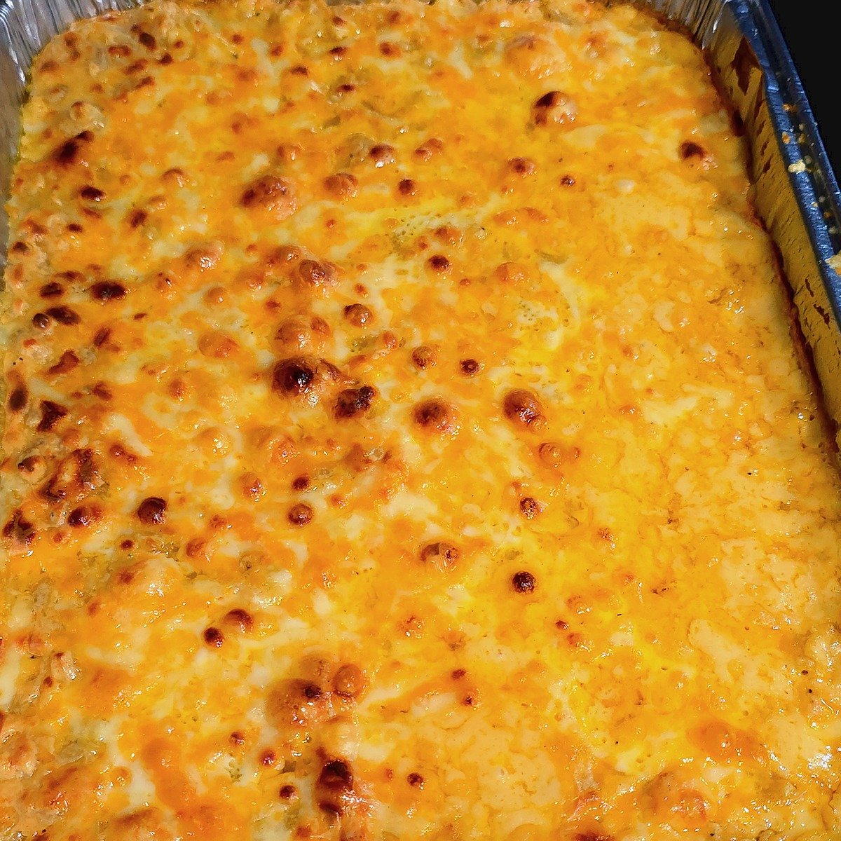 A full pan of baked mac and cheese with a bubbly, browned cheddar crust